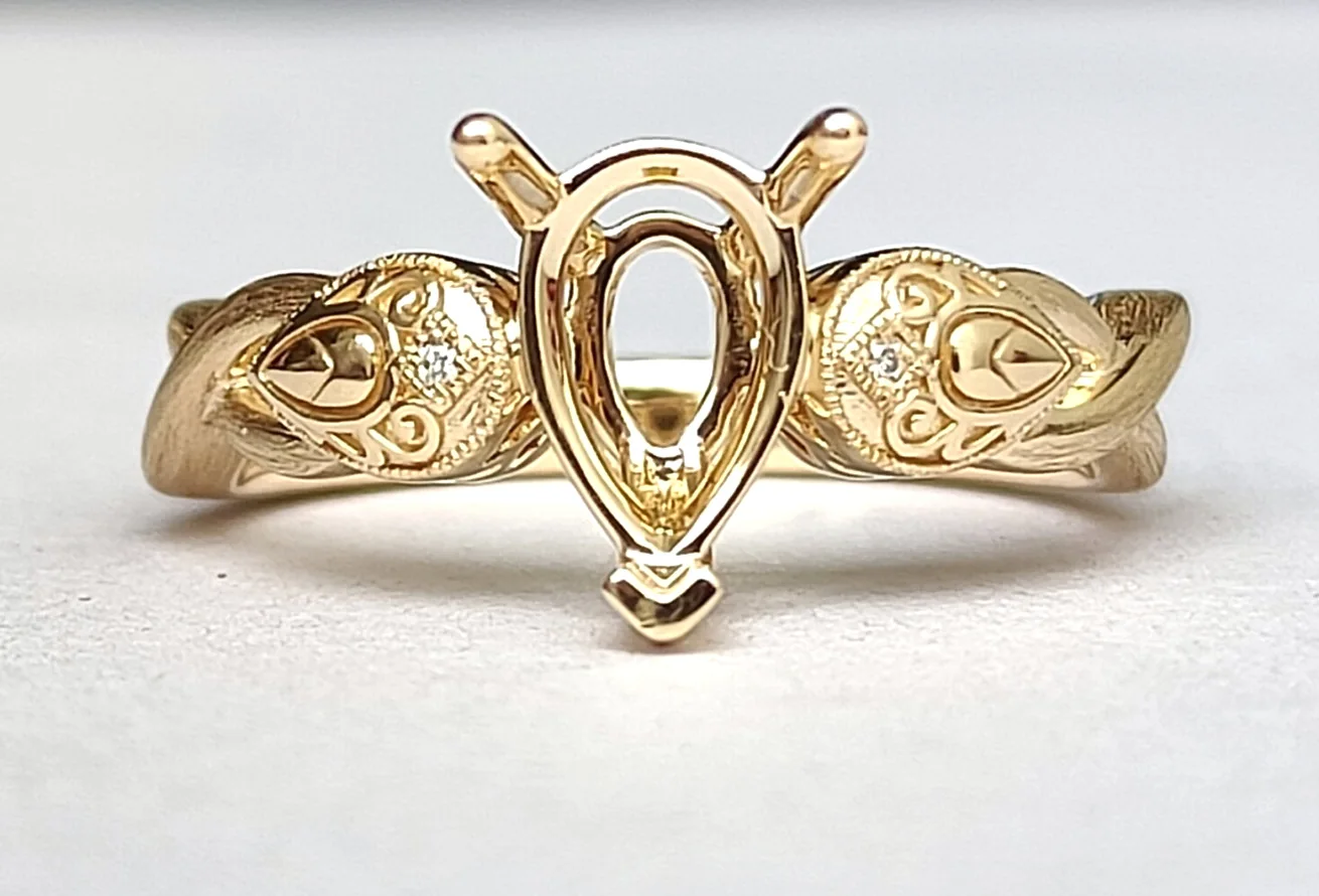 An 18ct yellow gold engagement ring from the front, with carved shoulders and open claws, before its pear centre stone was set.