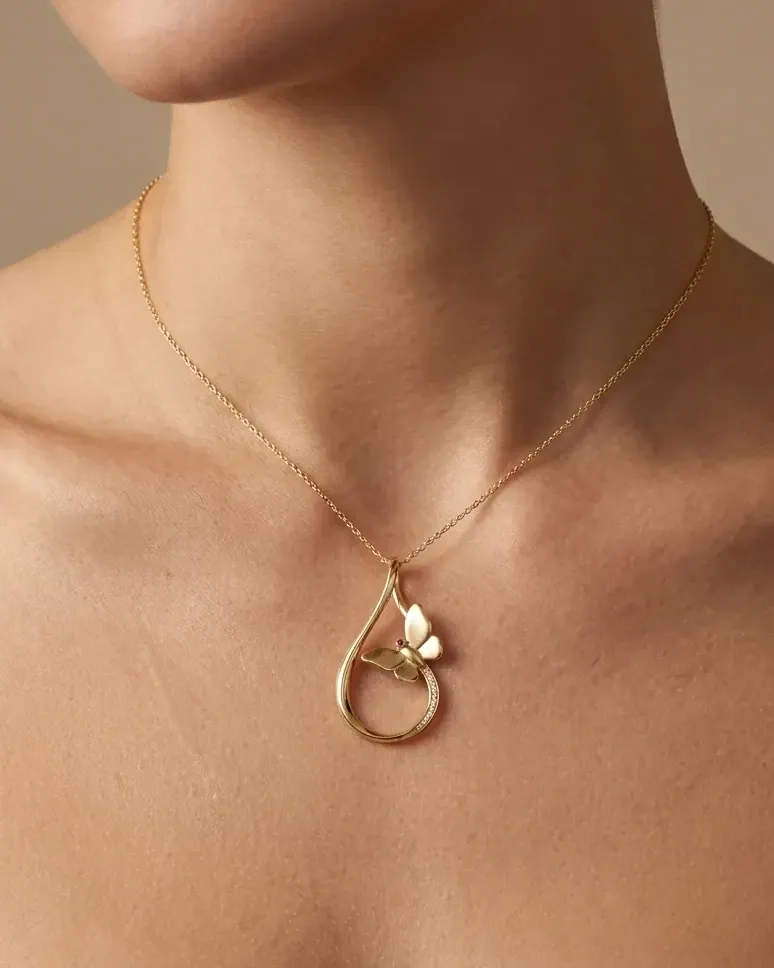 Design visualisation of the Parvaz Pendant worn at the neckline: a gold teardrop loop with a small butterfly, on a fine chain.