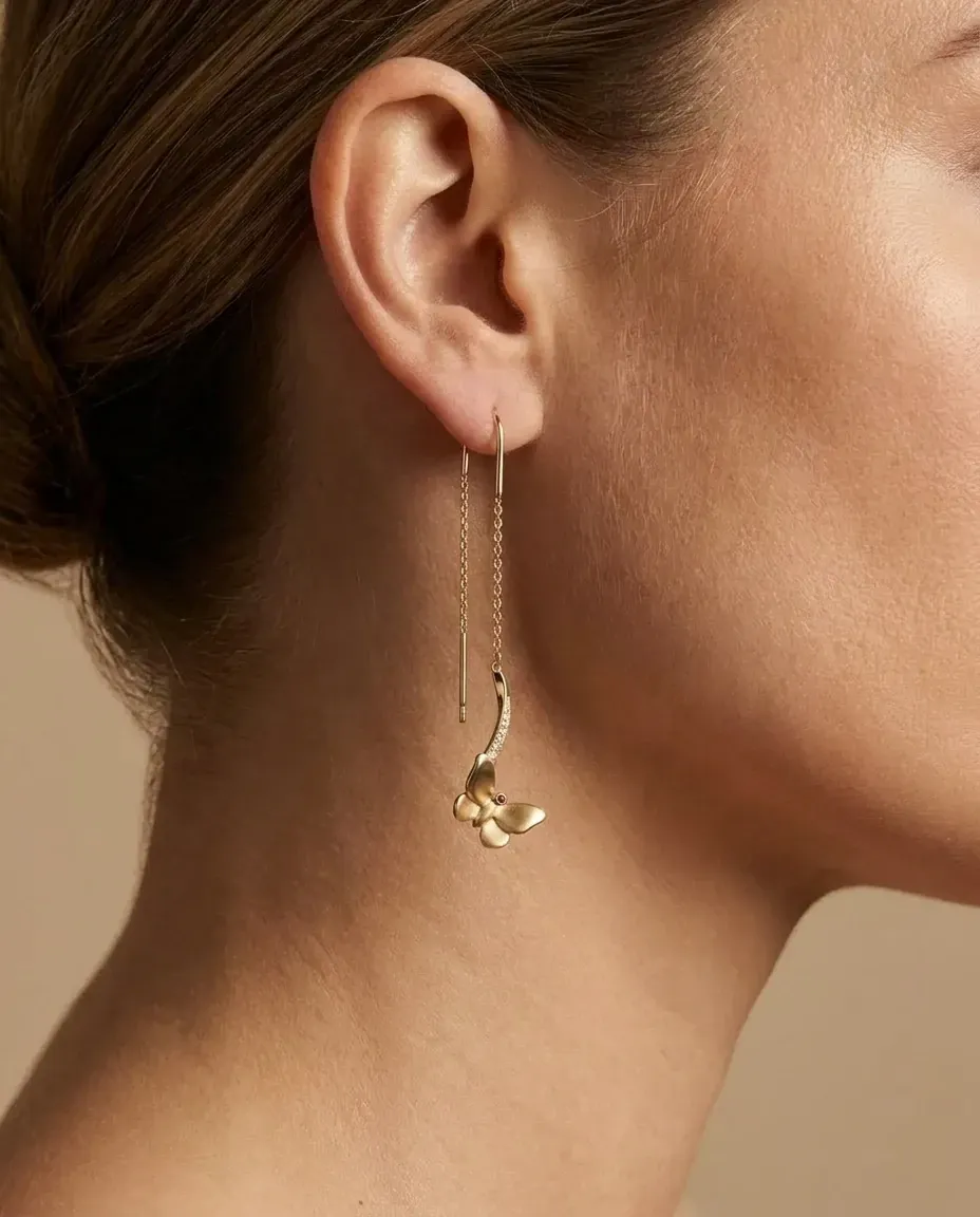 Design visualisation of the Parvaz Threader Earrings worn through the ear: a fine gold chain and ribbon ending in a small butterfly.